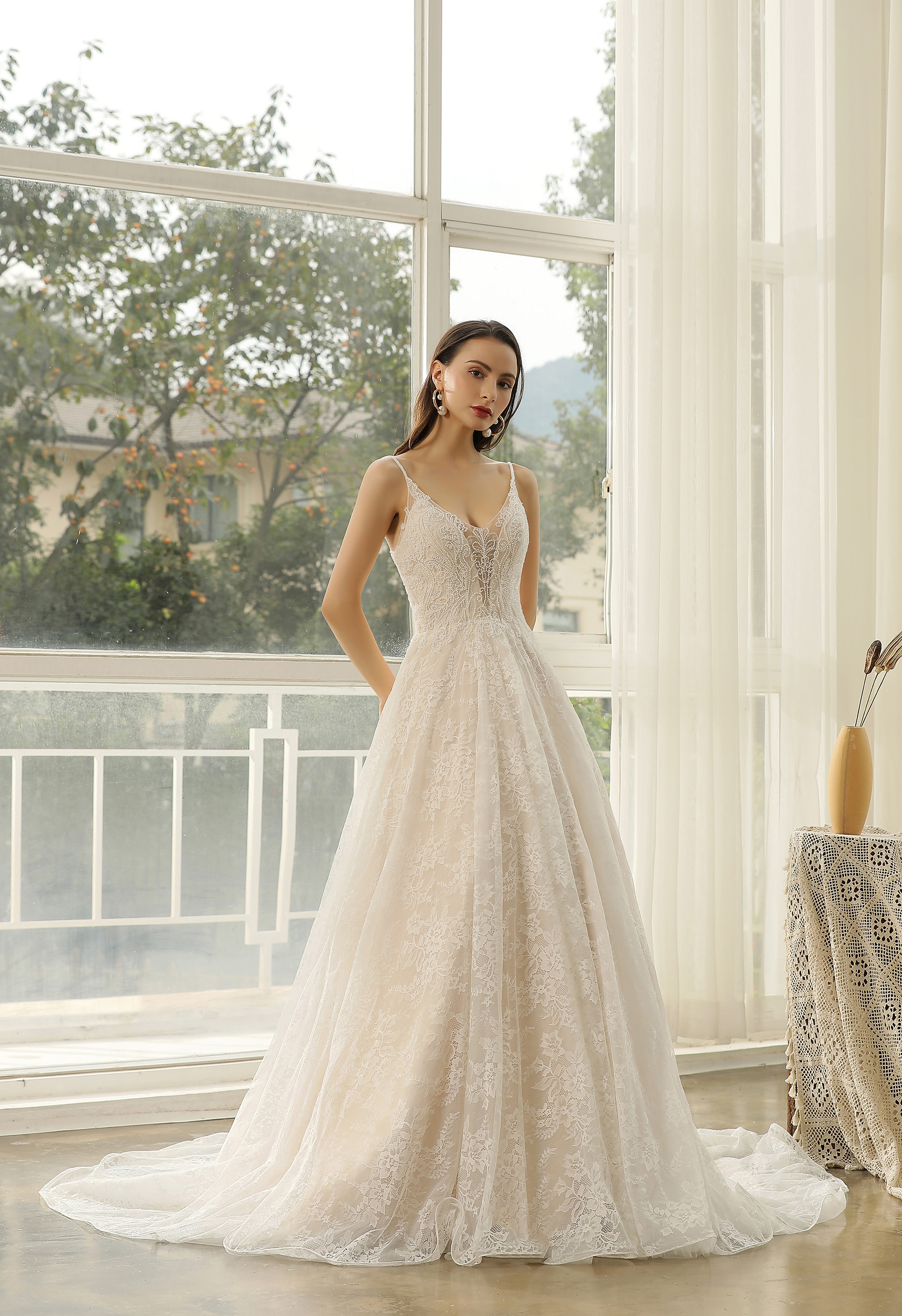 Bride in a sheer illusion-back wedding dress by a window
