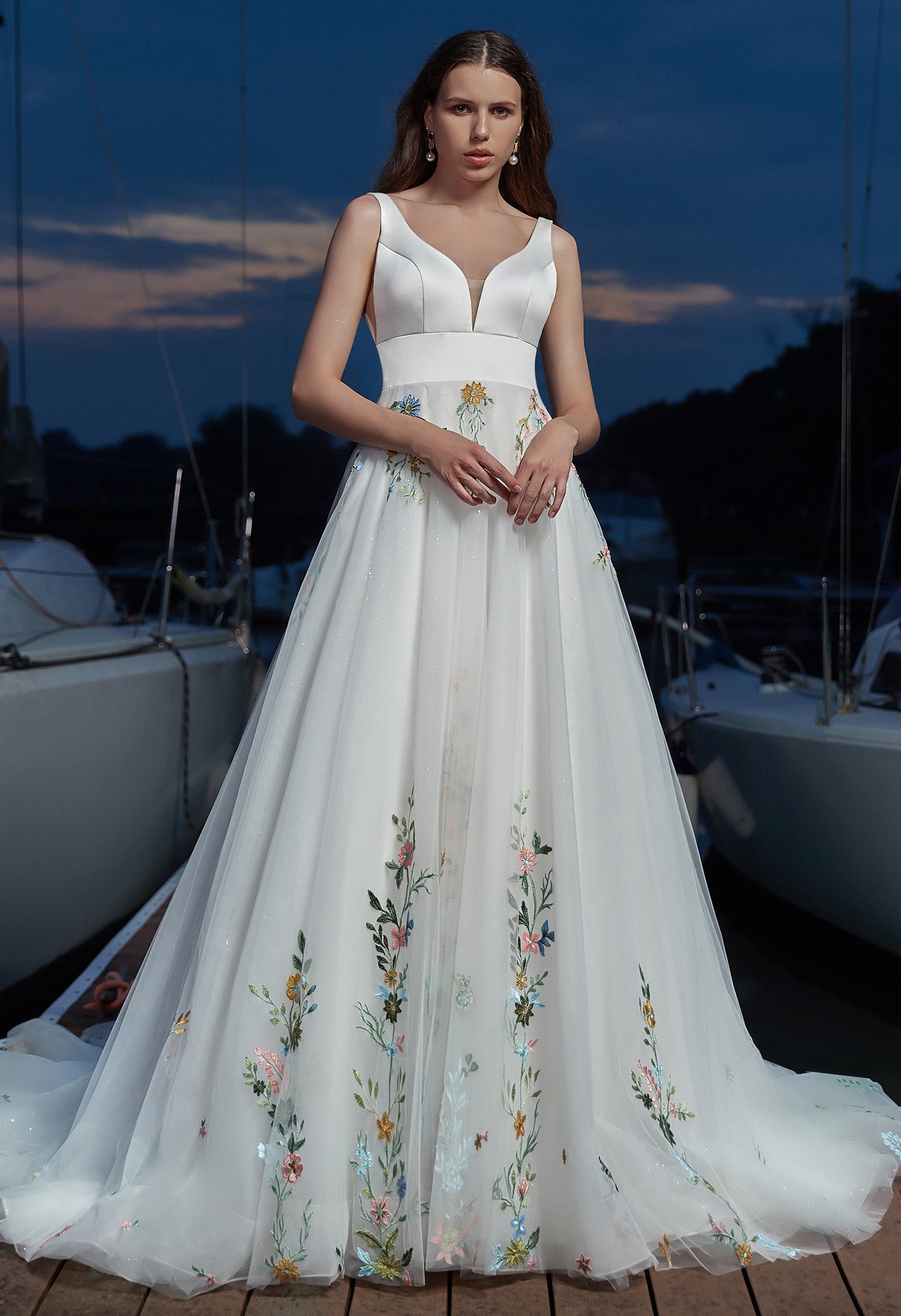 Bride in a floral embroidered wedding dress standing by a window