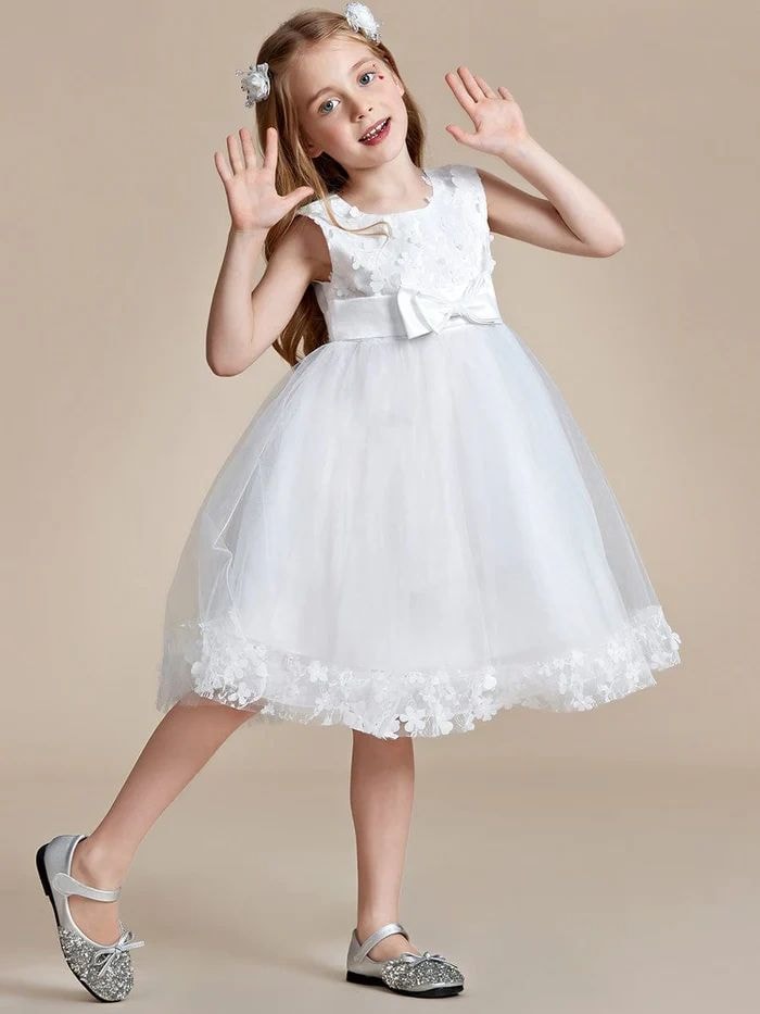 Young girl in a white floral flower girl dress posing playfully